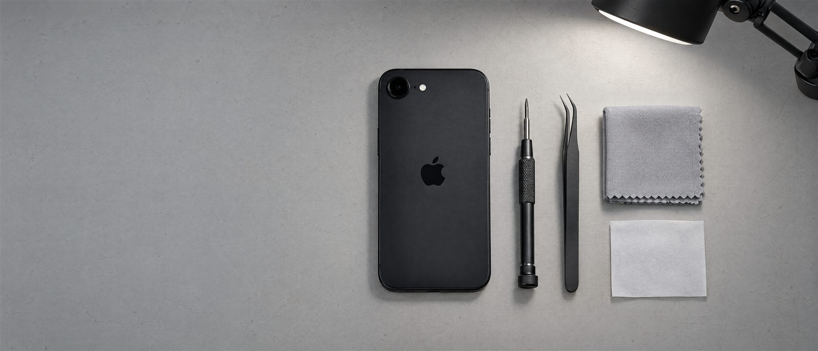 Editorial Revivo image: a clean inspection bench with a black iPhone and precision tools.